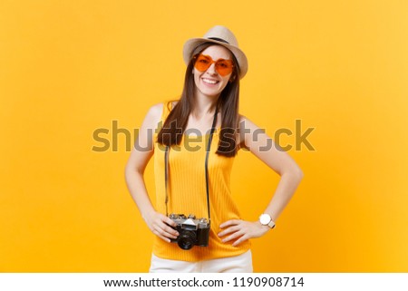 Happy traveler tourist woman in summer casual clothes, hat with retro vintage photo camera isolated on yellow orange background. Girl traveling abroad travel on weekends getaway. Air flight concept