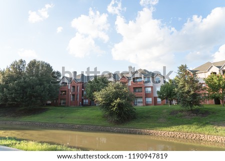 Typical multistory riverside apartment building complex surrounded by mature trees in Irving, Texas, USA.