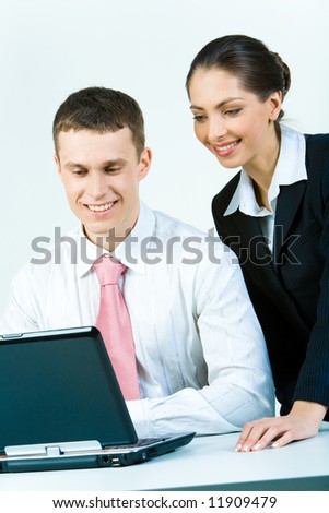 Photo of two young business people looking at the laptop
