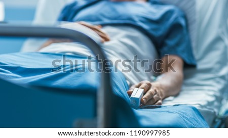 In the Hospital Sick Male Patient Sleeps on the Bed. Heart Rate Monitor Equipment is on His Finger. Royalty-Free Stock Photo #1190997985