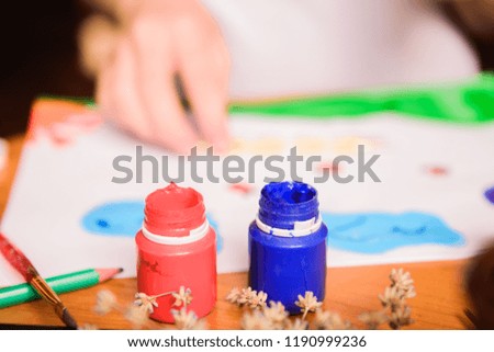 Unrecognizable child painting with watercolors. Kid drawing at white paper. The hands and paint brushes. Art for children. Drawing class