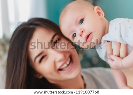 mother and her baby. A beautiful woman with dark hair and attractive facial features holds on her hands a very beautiful baby who smiles at the camera, looks at her mother is glad and happy.