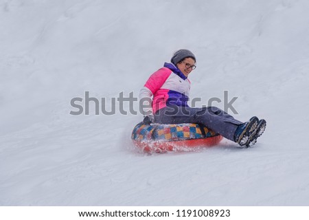 young woman slides on a tube from a snowy mountain