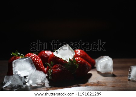 Fresh ripe strawberries on a wooden table and ice cubes with water
