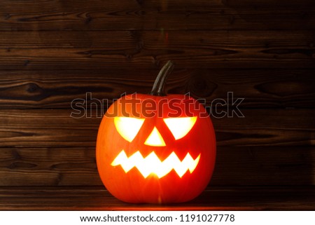 Halloween pumpkin head jack o lantern with candle inside on wooden background