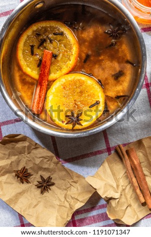 Preparation of hot mulled wine, ingredients in a saucepan, bright orange rings