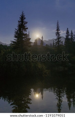 Moon above mountains and lake at night