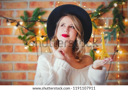 Portrait of a young cozy woman with Eiffel tower and Christmas lights on background