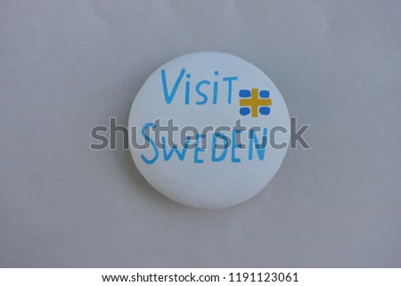 Visit Sweden, souvenir of a beautiful holiday in the scandinavian country on a painted stone over white sand