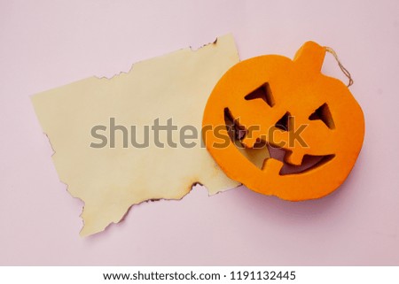 Halloween pumpkin with a burnt paper on a pink background