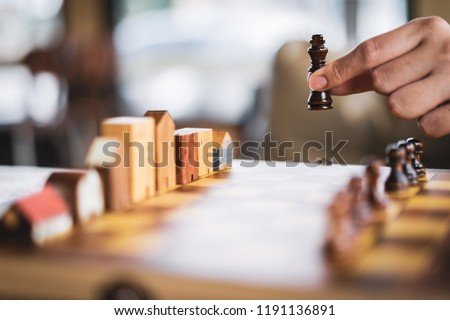 Hand of businessman moving Building and house models in chess game, competition success play. strategy, management or leadership concept 