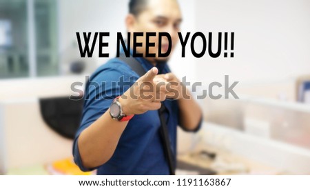 A man with abstract blurred background pointed his finger to the screen with text we need you. Close up image. 