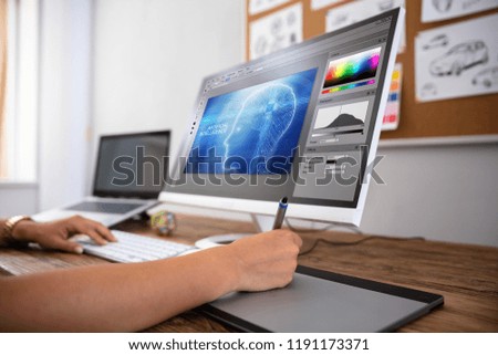 Female Designer Using Graphic Tablet While Working On Computer