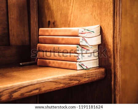 Stack of songbooks on a wooden bench in a church, so that the visitors can sing along together during the service.