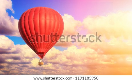 Red balloon against a blue cloudy sky. Sun rays and glare. Dreamy clouds. Aerostat. People in the basket. Fun. Summer entertainment. Romantic adventures. Royalty-Free Stock Photo #1191185950