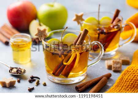 Apple mulled cider with spices in glass cup. Grey background. Close up.