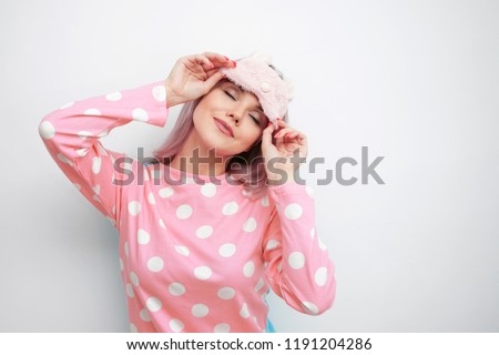 Beautiful young blonde in pink pajamas and a sleep mask. girl woke up in the morning, concept of cheerful beginning of day