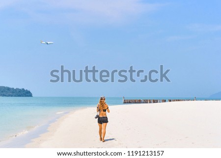 Beautiful woman is making a picture how plane is landing on the tropical island