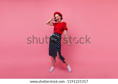 Full-length portrait of charming female model in vintage skirt. Studio photo of cheerful brunette girl in beret expressing positive emotions.