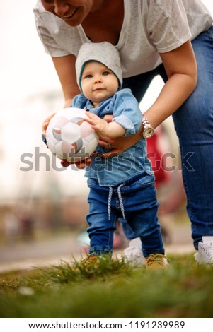 Happy family having fun at park - cute baby boy with a ball in hands