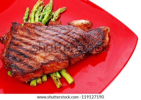 meat table : grilled beef fillet with asparagus served on red dish isolated over white
