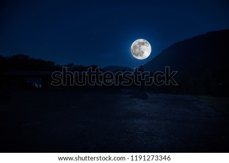 Mountain Road through the forest on a full moon night. Scenic night landscape of dark blue sky with moon