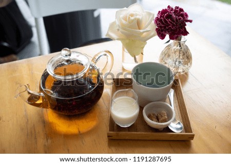 White rose next to fancy tea pot