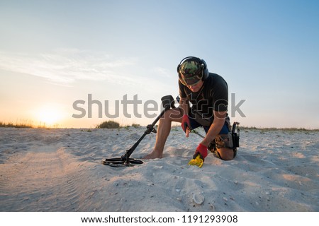 Man with a metal detector on a sea sandy beach Royalty-Free Stock Photo #1191293908