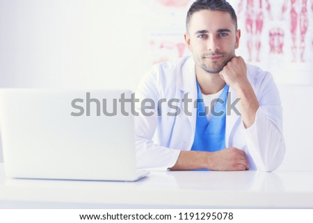 Young and confident male doctor portrait standing in medical office.