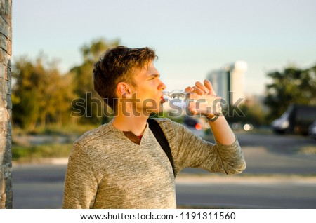 Side view portrait of teen drinking bottled water on the street 