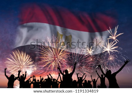 Happy people are looking holiday fireworks with flag of Egypt in sky, independence day