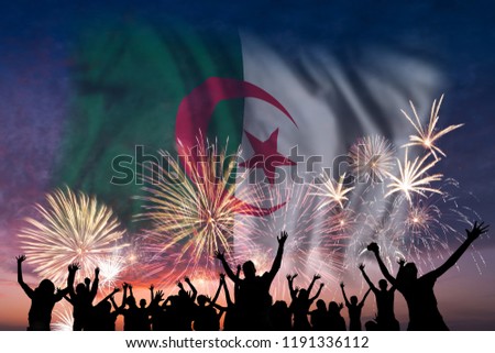 Happy people are looking holiday fireworks with flag of Algeria in sky, independence day