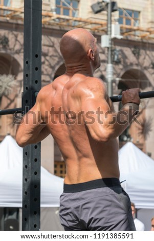 Athlete muscular fitness male model pulling up on horizontal bar in a gym. Closeup of strong athlete doing pull-up on horizontal bar. vertical photo