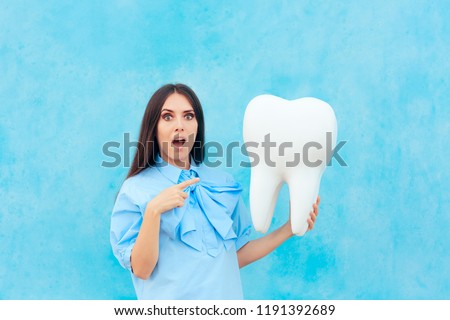 Funny Woman Holding Oversized Tooth in Dentist Concept Image. Cute girl with big wisdom molar or implant mock-up model
 Royalty-Free Stock Photo #1191392689