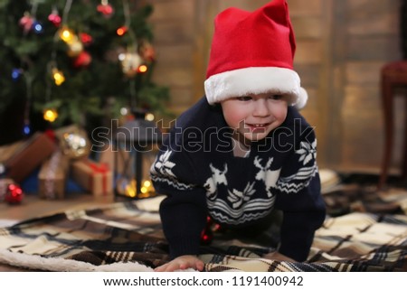 little child sitting in front of a Christmas tree and playing with toys
