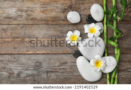 Flat lay composition with bamboo branches and spa stones on wooden background. Space for text