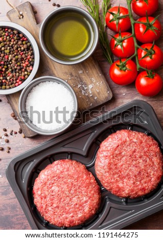 Plastic tray with raw minced homemade grill beef burgers with spices and herbs. Top view and space for text.
