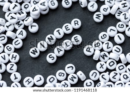 Words WINTER SALE  made from small white letters on black stone background