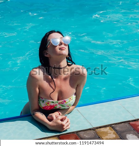 girl in the pool with transparent water, in a swimsuit and sunglasses, in the rays of the midday sun.