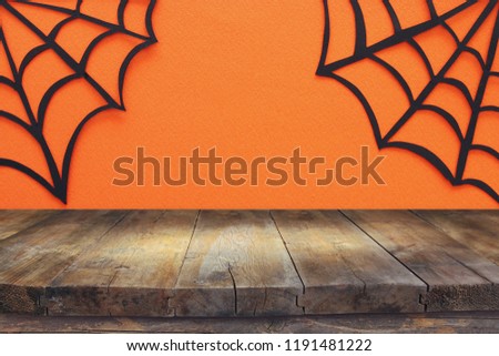 Halloween holiday concept. Empty rustic table in front of Spider webs over orange background. Ready for product display montage