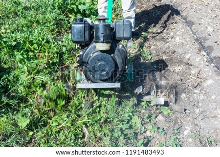 Abstract and conceptual of motor hoe at work. gardener working in the garden with rototiller , tiller tractor, cutivator, miiling machine. Man plowing the garden
