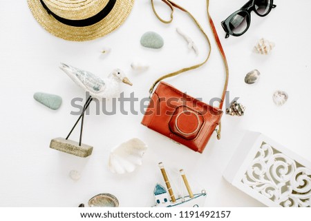 Modern composition with bird figurine, toy boat, retro camera, sunglasses, seashells and straw hat on white background. Flat lay, top view travel photographer concept.