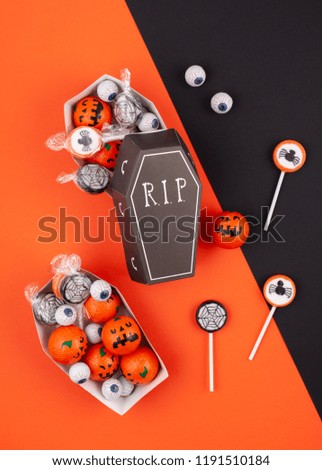 Flat lay of candies and chocolates in the coffins as halloween treats, accessory decoration Happy Halloween festival background concept. 