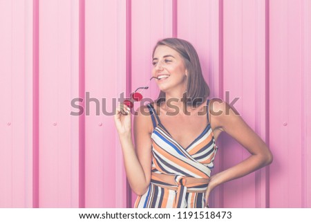 Portrait of trendy girl on pastel pink wall outdoors.