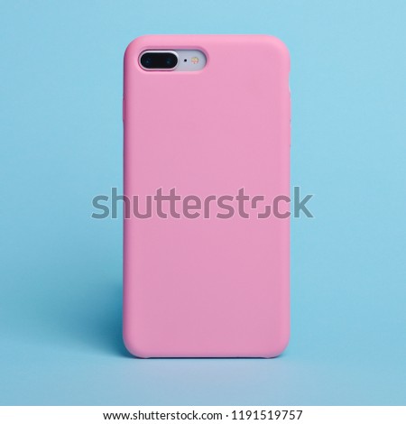 Smart phone on a light blue background in a pink plastic case back view. Template of phone case