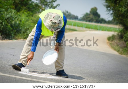 Workers are painting white lines on countryside road.