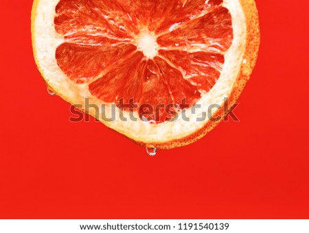 fresh bright grapefruit with water drops on red background, copy space