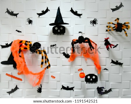 Halloween concept with black skull in wizard hat, black bats, pumpkins and orange-black spiders with orange spider webs on white background.
