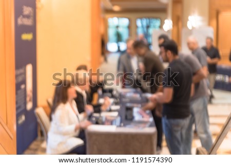 Blurred image side view diverse participants at registration check-in workshop table. Multiethnic people sign-up at conference hotel lobby and received instruction, event package from support staff