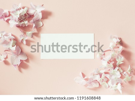 Styled feminine flat lay on pale pastel pink background, top view. Minimal woman's desktop with blank page mock up, open envelope and  pink  flower, Creative concept, empty greeting card